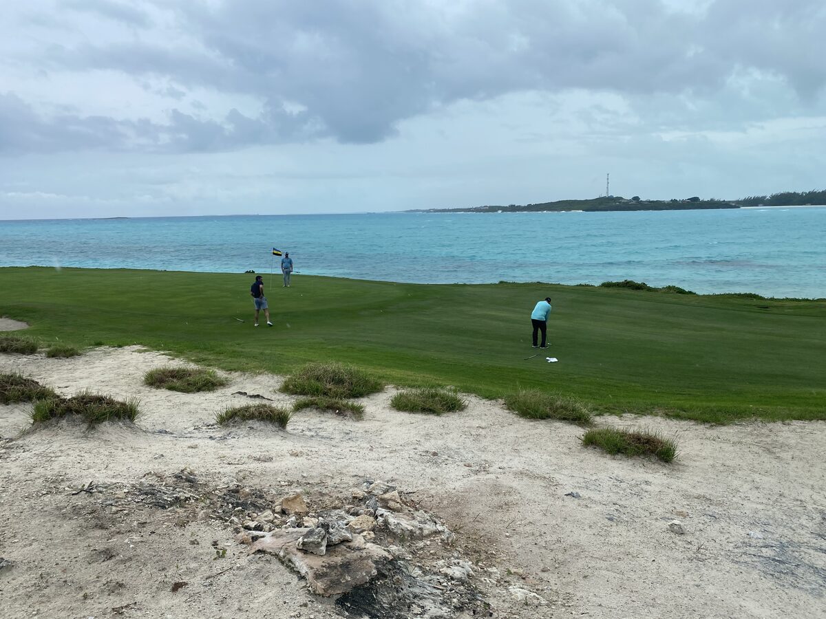 Golfer putting on coastline green at Sandals Emerald Bay