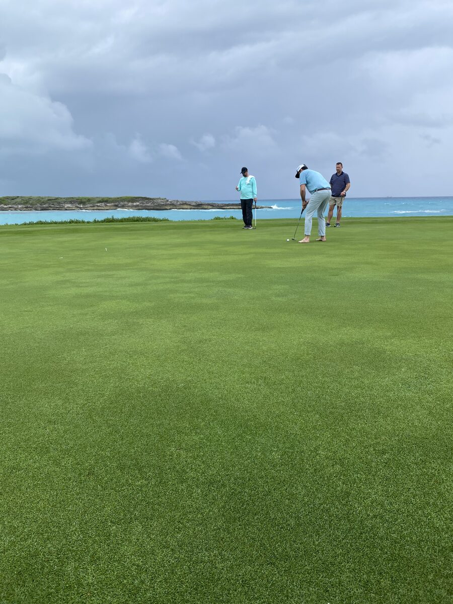 Golfers on cliffside putting green overlooking the Bahamian coast